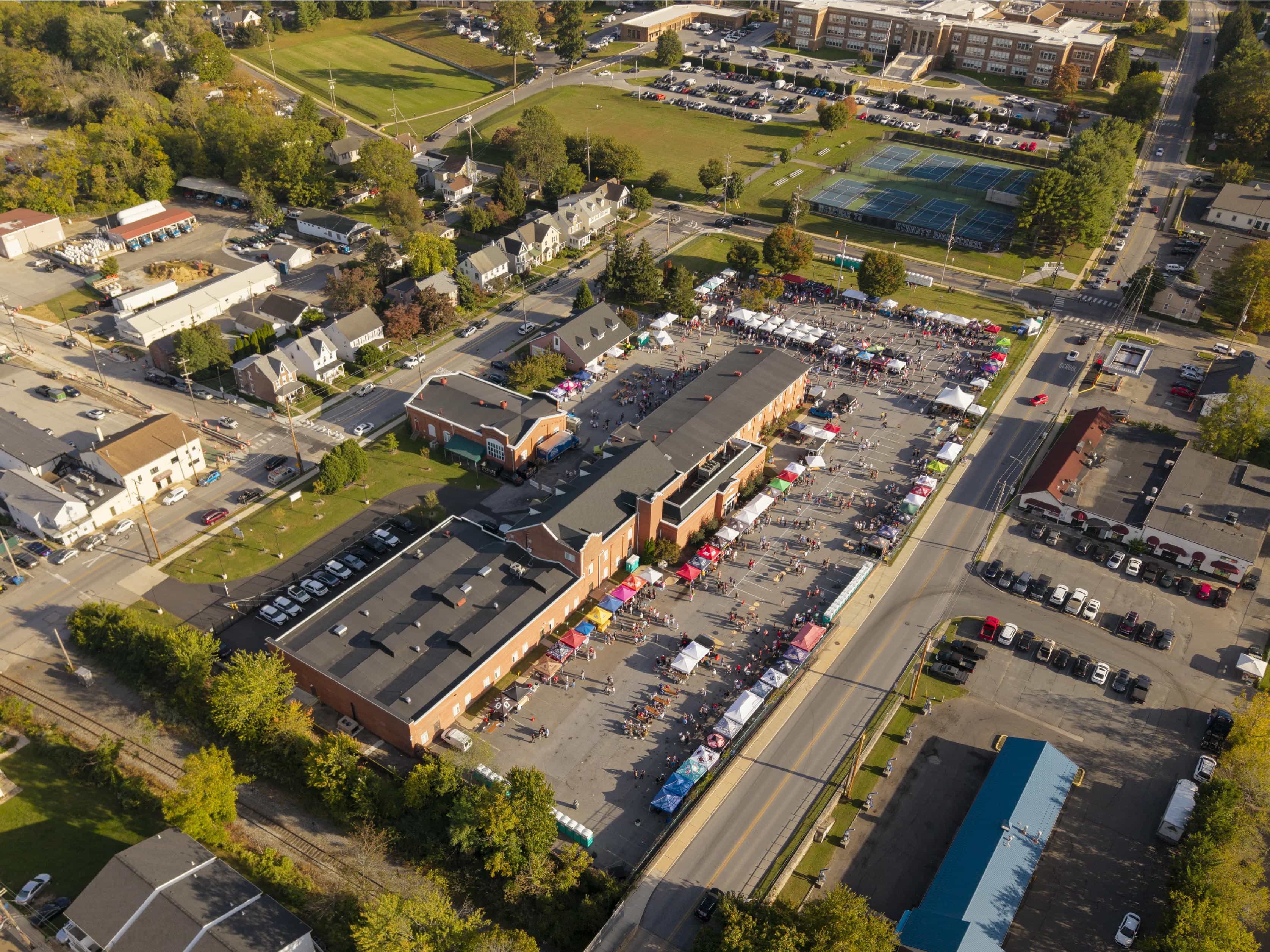 Aerial view of a street event with vendor stalls beside athletic fields